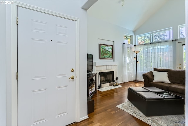 living room featuring hardwood / wood-style floors, lofted ceiling, and a tiled fireplace