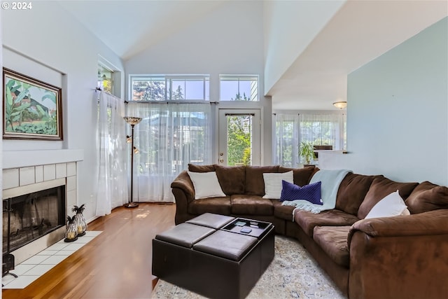 living room with a fireplace, high vaulted ceiling, and light hardwood / wood-style flooring