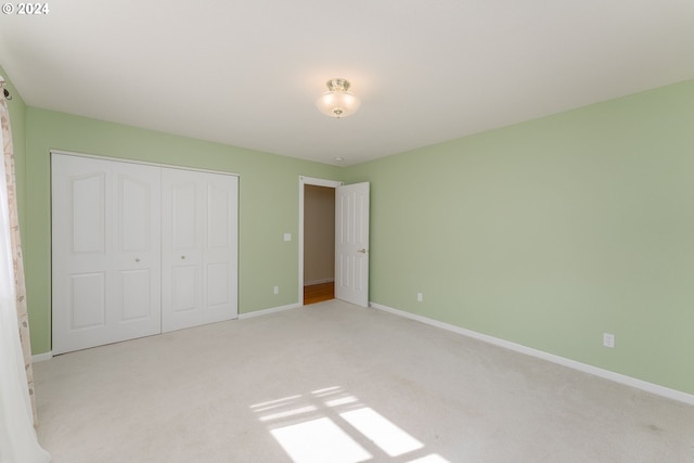 unfurnished bedroom featuring light carpet and a closet