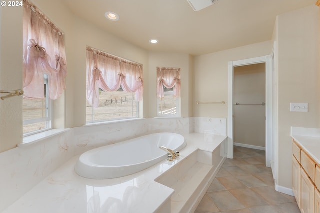 bathroom with tile patterned floors, tiled tub, and vanity