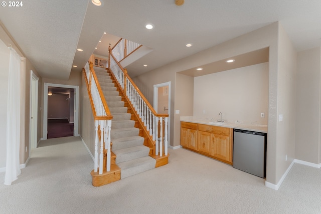 bar with light carpet, light brown cabinets, stainless steel fridge, and sink