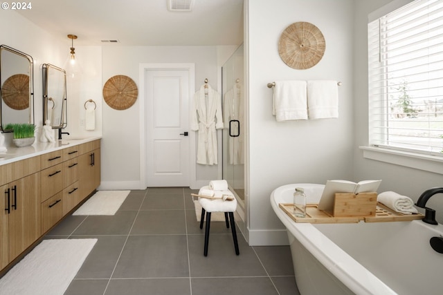 full bath featuring double vanity, visible vents, a freestanding tub, baseboards, and tile patterned floors