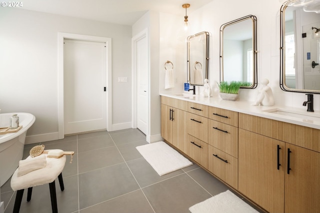 full bath featuring double vanity, tile patterned flooring, a sink, and baseboards