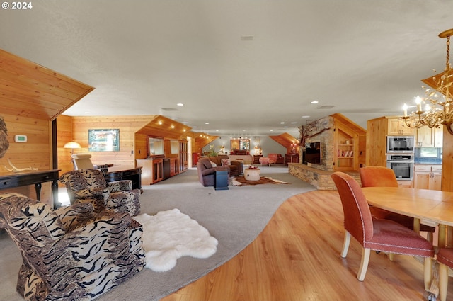 living room featuring built in shelves, a notable chandelier, wood walls, light carpet, and a fireplace