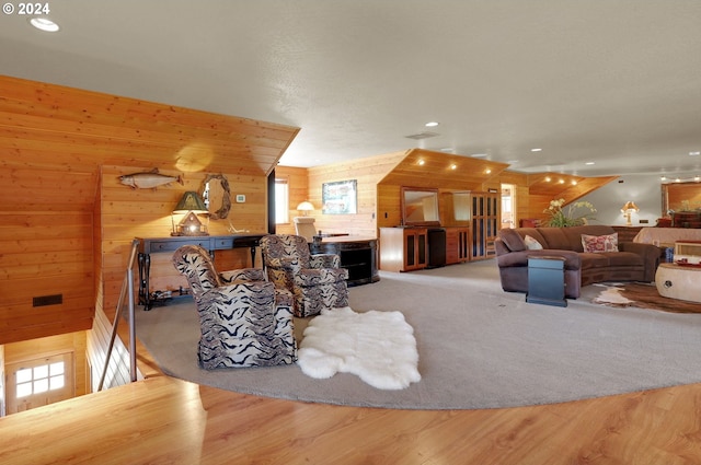 living room with light hardwood / wood-style flooring, lofted ceiling, and wood walls