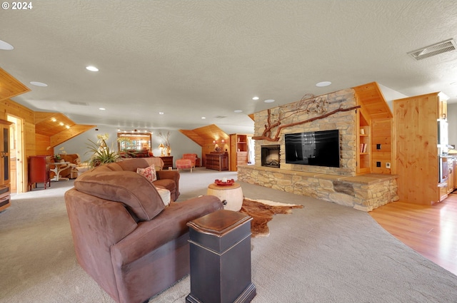 living room with a stone fireplace, wooden walls, a textured ceiling, and light wood-type flooring