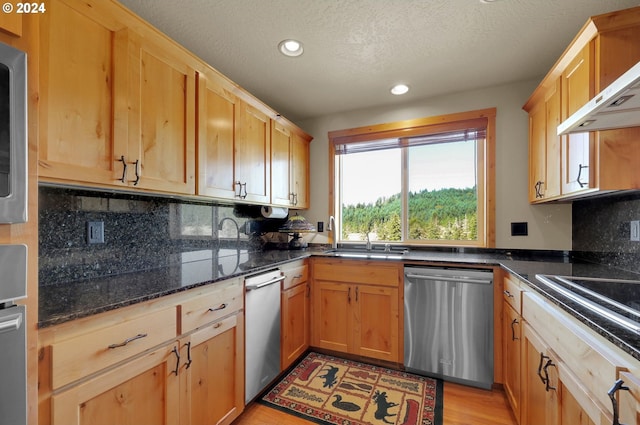 kitchen featuring backsplash, dishwasher, sink, and dark stone counters