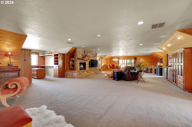 living room featuring a textured ceiling, a stone fireplace, a wealth of natural light, and wood walls