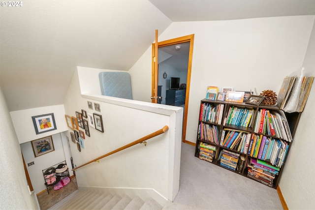 stairway featuring lofted ceiling, carpet flooring, and baseboards