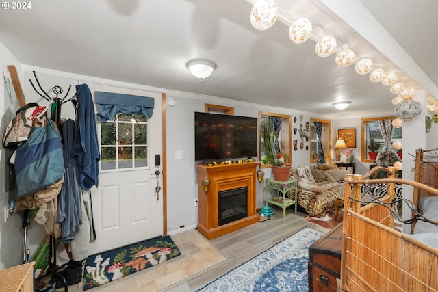 living room featuring crown molding, wood finished floors, and a glass covered fireplace