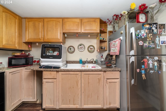 kitchen featuring freestanding refrigerator, black microwave, a sink, and light brown cabinetry