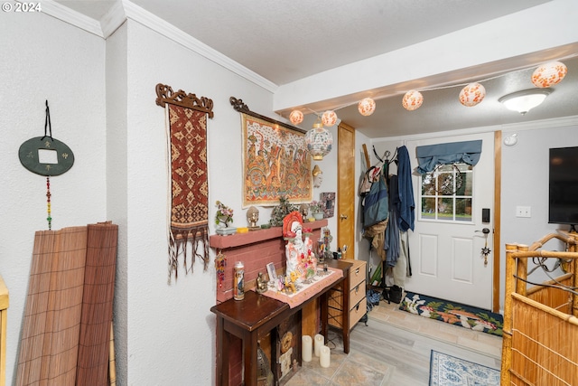 foyer entrance with ornamental molding and wood finished floors