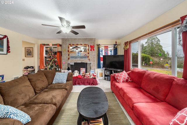 living room featuring ceiling fan, a fireplace, and carpet