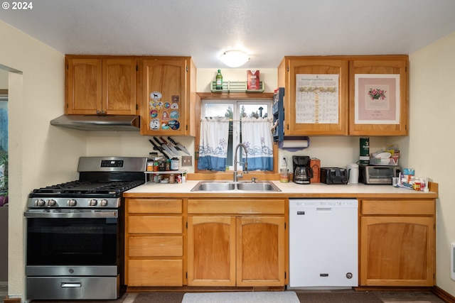 kitchen with dishwasher, gas range, light countertops, under cabinet range hood, and a sink