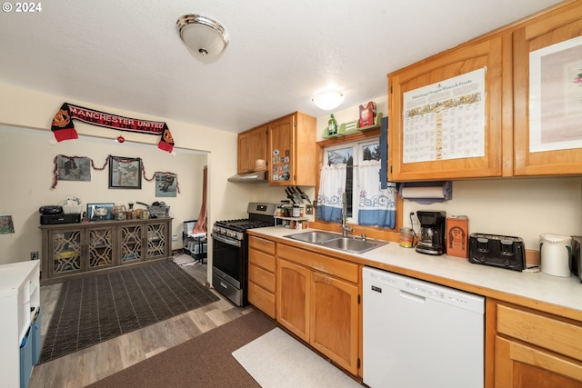 kitchen featuring light countertops, a sink, wood finished floors, stainless steel gas range, and dishwasher