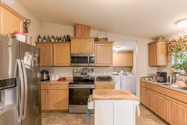 kitchen with appliances with stainless steel finishes, washing machine and dryer, lofted ceiling, and light tile floors