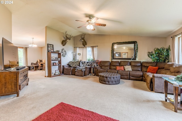 carpeted living room featuring lofted ceiling, ceiling fan with notable chandelier, and a healthy amount of sunlight