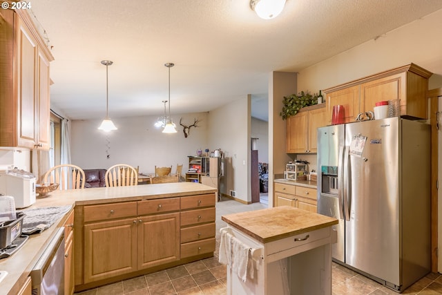 kitchen with decorative light fixtures, light brown cabinets, a kitchen island, light tile floors, and stainless steel appliances