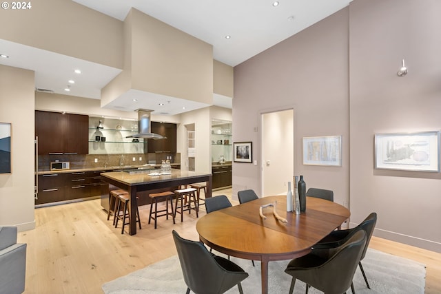 dining room featuring a high ceiling, light hardwood / wood-style flooring, and sink