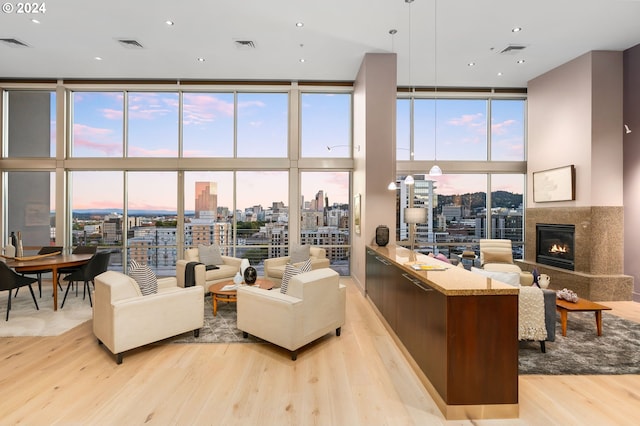 living room featuring a premium fireplace, a towering ceiling, expansive windows, and light hardwood / wood-style floors