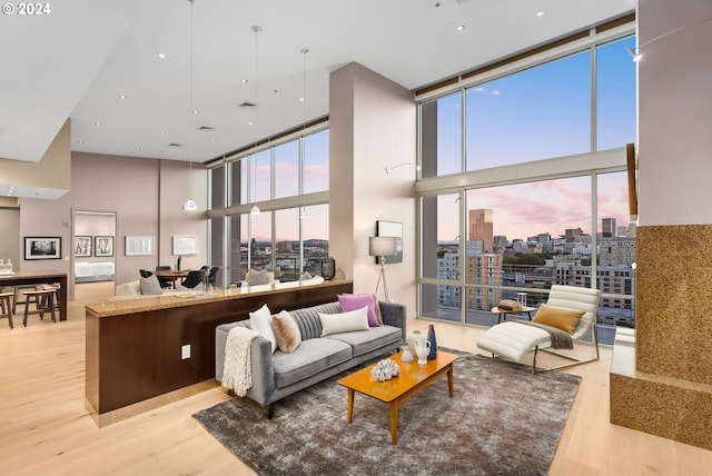 living room with a high ceiling, light hardwood / wood-style floors, and floor to ceiling windows