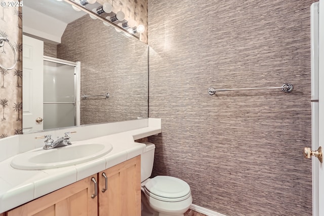 bathroom featuring vanity, toilet, and a shower with shower door