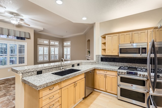 kitchen featuring kitchen peninsula, stainless steel appliances, ceiling fan, sink, and light brown cabinets