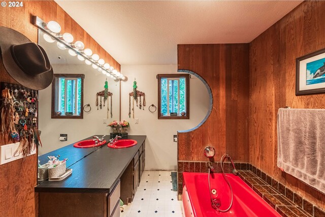 bathroom featuring wooden walls, vanity, tile patterned floors, and a bathing tub