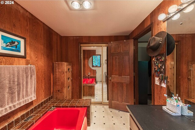 bathroom with a tub, wood walls, and vanity