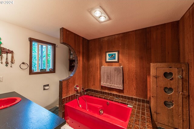 bathroom featuring vanity, wood walls, a textured ceiling, and a tub