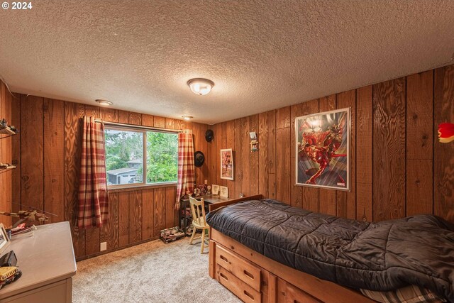 bedroom with light colored carpet, wooden walls, and a textured ceiling