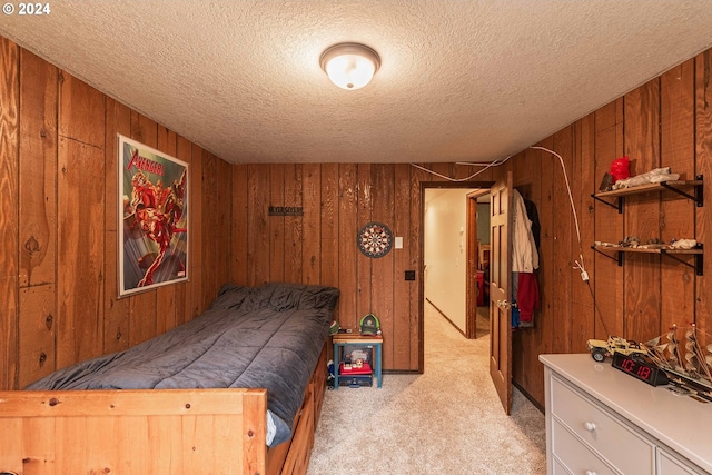 carpeted bedroom featuring a textured ceiling and wooden walls