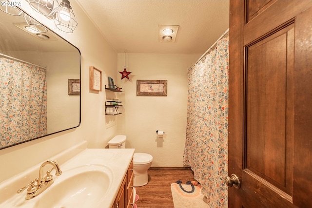 full bathroom with a textured ceiling, vanity, toilet, and wood finished floors