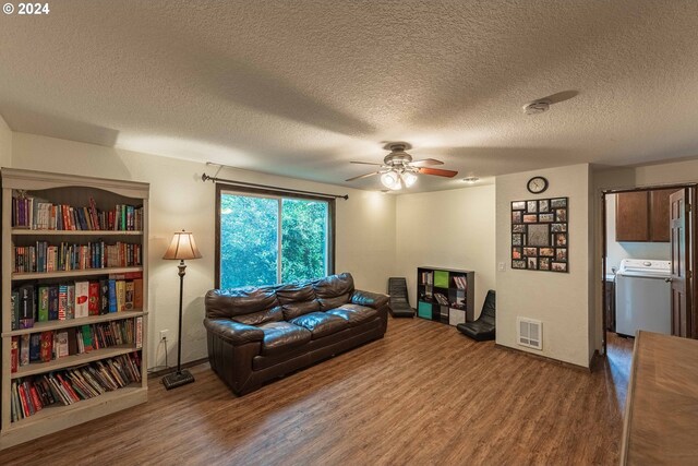 living room featuring washer / dryer, a textured ceiling, and hardwood / wood-style floors