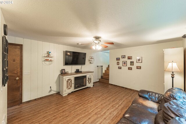 living room with a textured ceiling, hardwood / wood-style floors, and ceiling fan