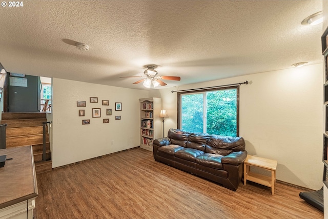 living area with a textured ceiling, wood finished floors, and a ceiling fan