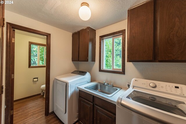 washroom featuring a textured ceiling, washer and dryer, hardwood / wood-style floors, cabinets, and sink