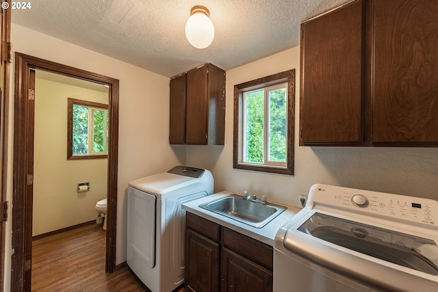 laundry room featuring cabinet space, a sink, a textured ceiling, separate washer and dryer, and wood finished floors