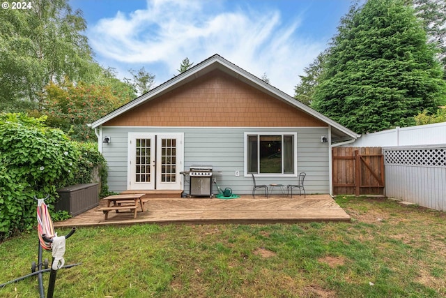 rear view of house with a lawn, fence, french doors, and a wooden deck