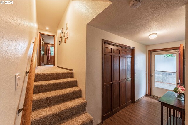 stairs featuring a textured ceiling and hardwood / wood-style floors