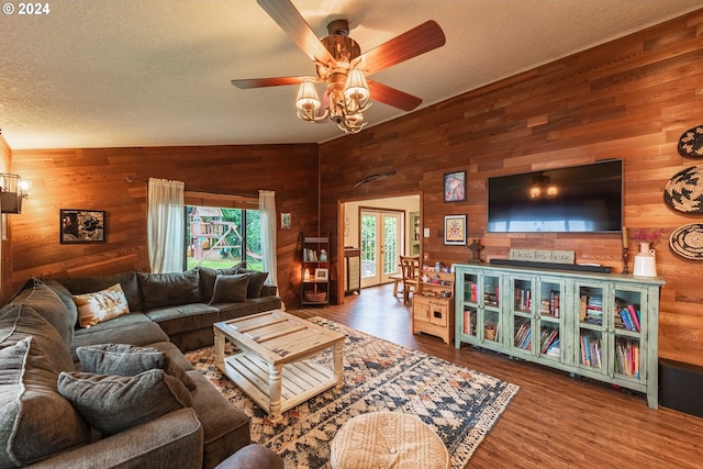 living area with a textured ceiling, wood finished floors, a ceiling fan, and wooden walls