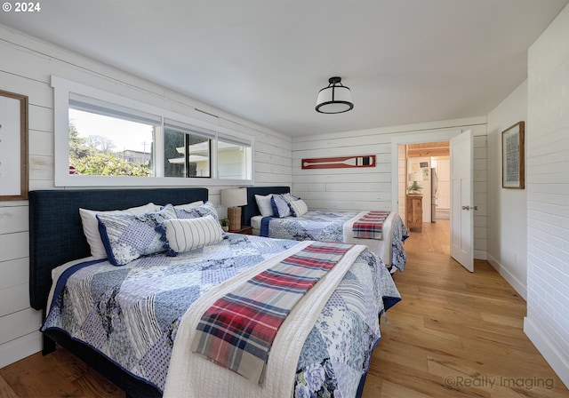 bedroom with light hardwood / wood-style flooring and wooden walls