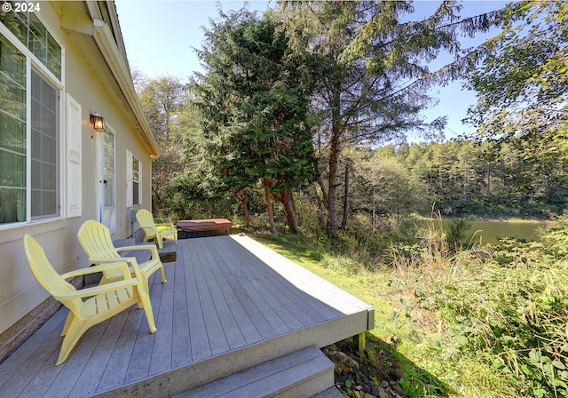 wooden deck featuring a covered hot tub and a water view