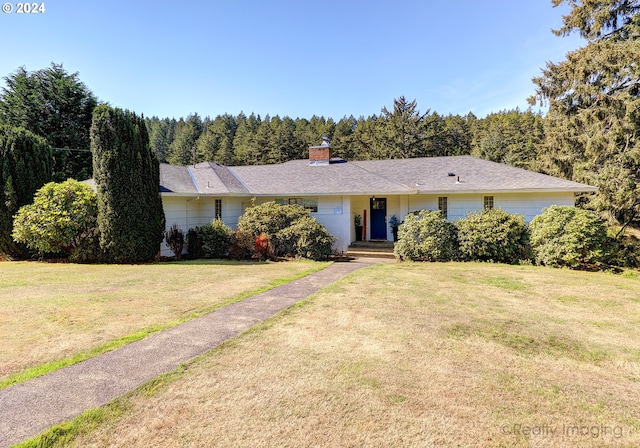 ranch-style home with a chimney and a front lawn