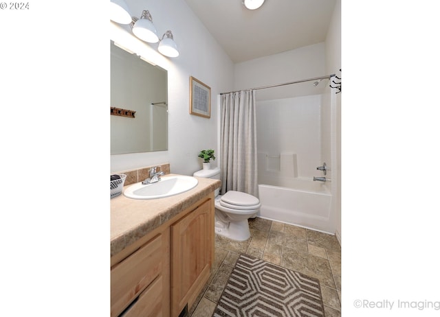 bathroom with toilet, shower / bathtub combination with curtain, vanity, and stone finish flooring