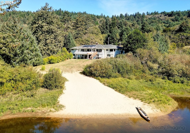 birds eye view of property featuring a forest view and a water view