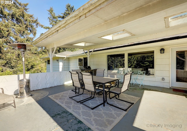view of patio featuring a grill, fence, and outdoor dining area