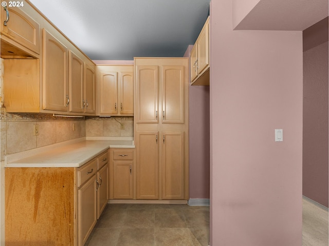 kitchen with backsplash, light countertops, light brown cabinets, and baseboards