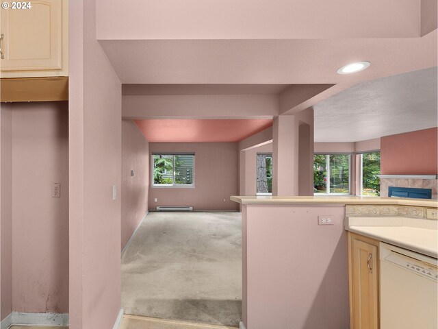 kitchen with cream cabinets, light colored carpet, white dishwasher, a fireplace, and a baseboard heating unit