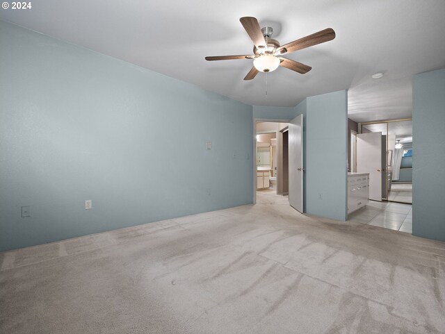 unfurnished bedroom featuring light colored carpet, ensuite bathroom, and ceiling fan